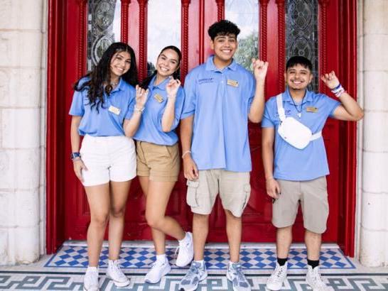 Orientation leaders st和ing in front of the red doors.